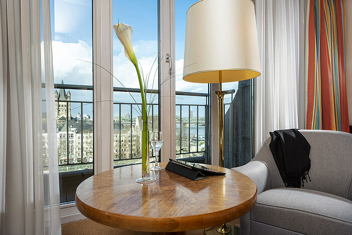 Habitación Classic en el Maritim Hotel Colonia con vistas al Rin, área de descanso acogedora y mesa decorada con elegancia.