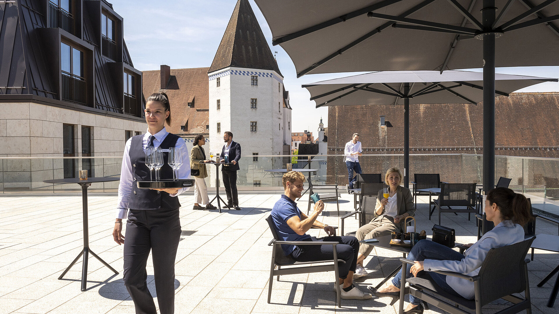 Guests enjoy drinks on the rooftop terrace of Maritim Hotel Ingolstadt with a view of the old town.