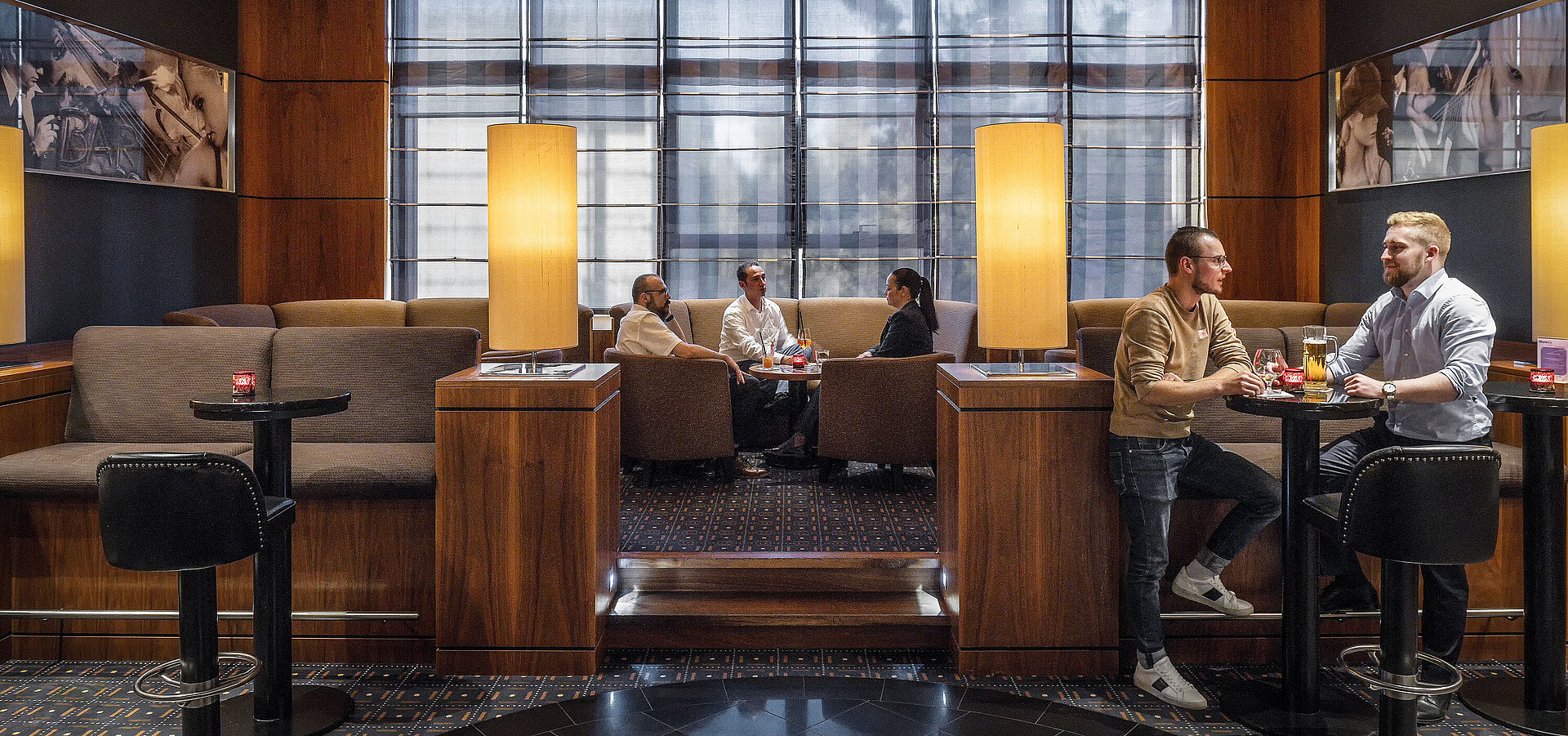 Aree salotto accoglienti nel bar dell'hotel al Maritim Hotel Düsseldorf con illuminazione moderna e ospiti che chiacchierano.