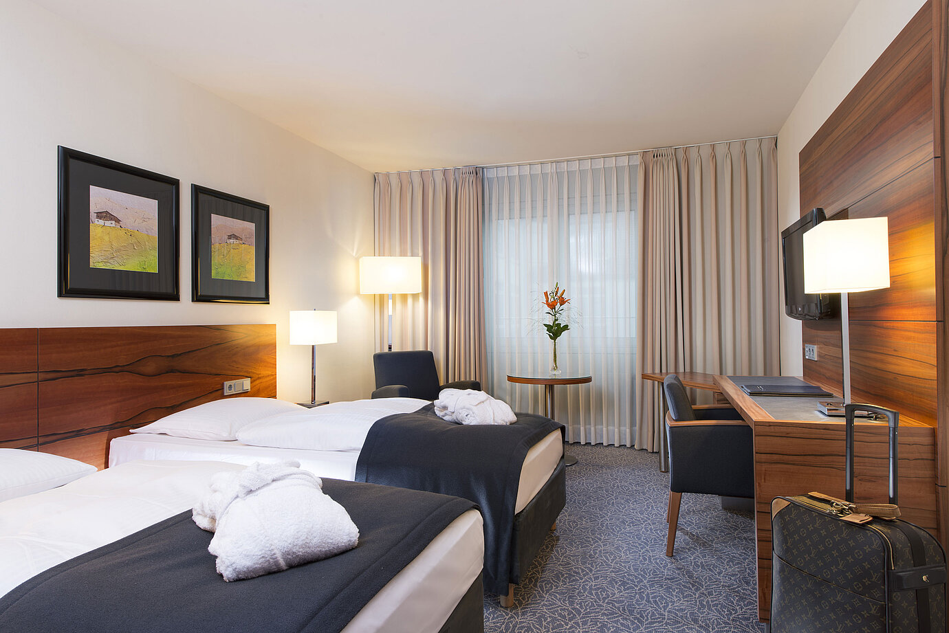 Confortable habitación twin en el Maritim Hotel Múnich. Con camas separadas, escritorio,TV y zona de estar junto a la ventana