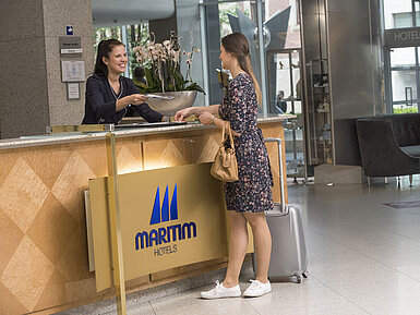 Accoglienza cordiale alla reception del Maritim proArte Hotel Berlin con personale sorridente durante il check-in.