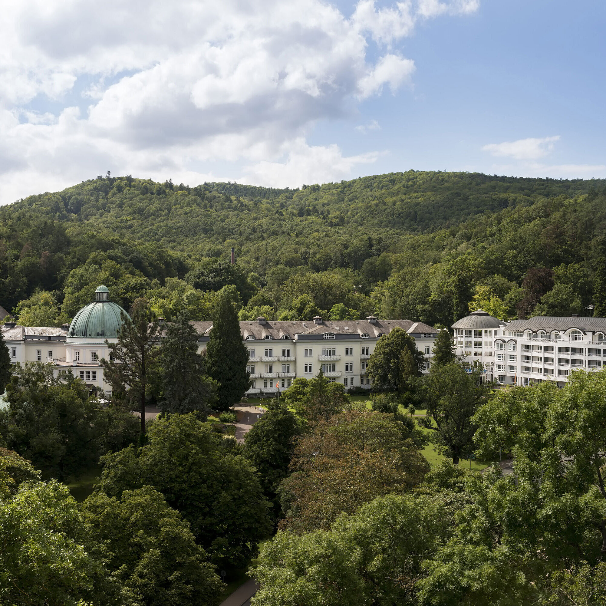Exterior view of Maritim Hotel Bad Wildungen surrounded by lush greenery in summer