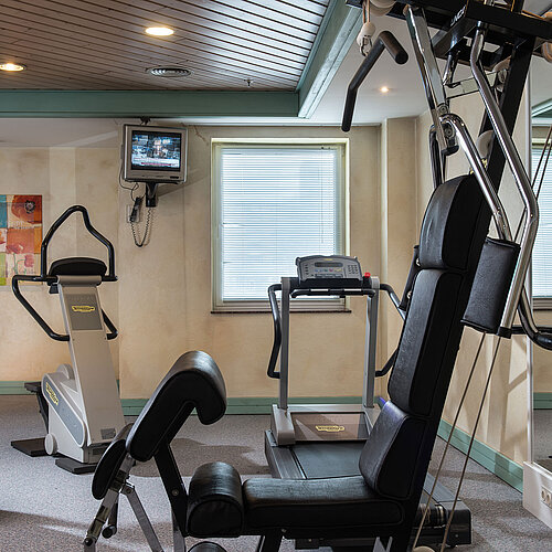 Salle de fitness au Maritim Hotel Magdeburg avec équipements modernes comme tapis de course, vélo et station de musculation.