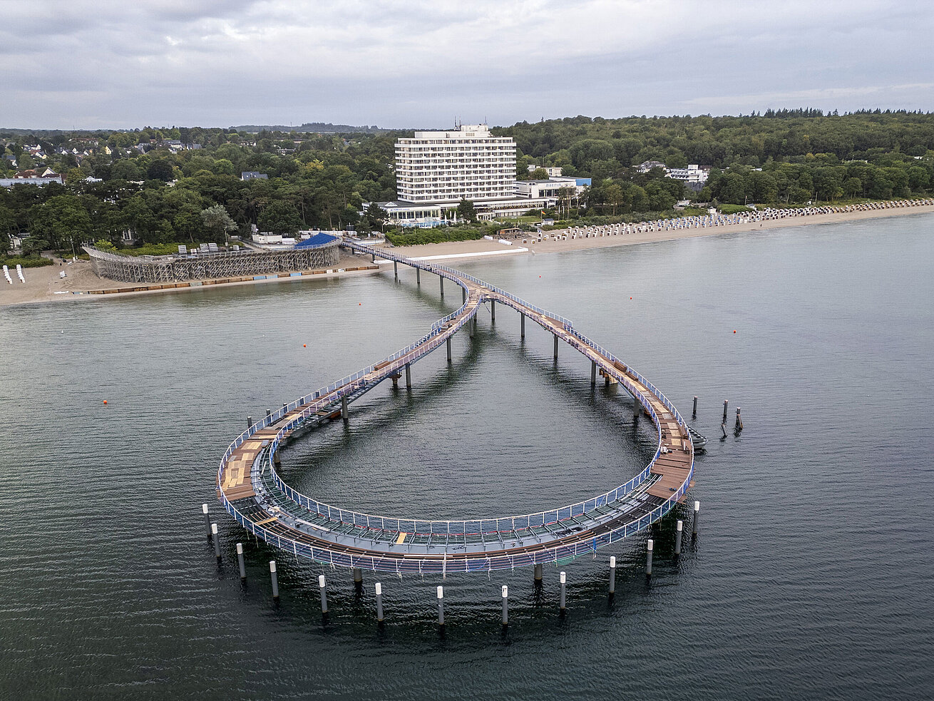 Muelle frente al Maritim Seehotel Timmendorfer Strand con agua tranquila y cielo azul.