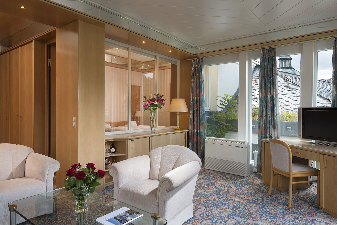Stylish living area with armchairs, TV, large windows and roof view at Maritim Hotel Bad Wildungen