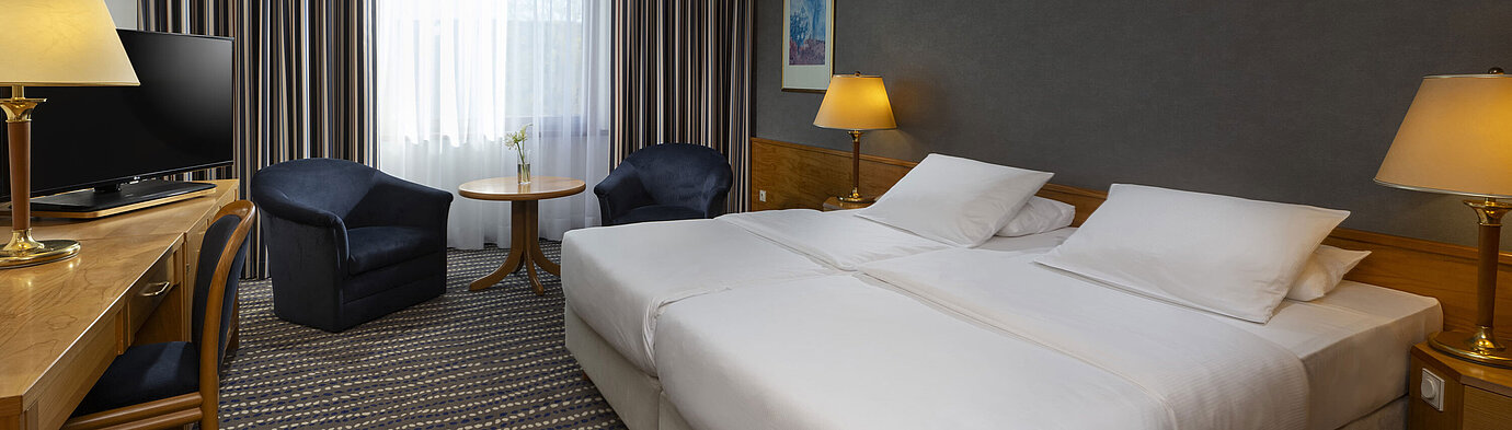 Hotel room with double bed, TV, desk, and cozy seating area, ideal for relaxation and comfort