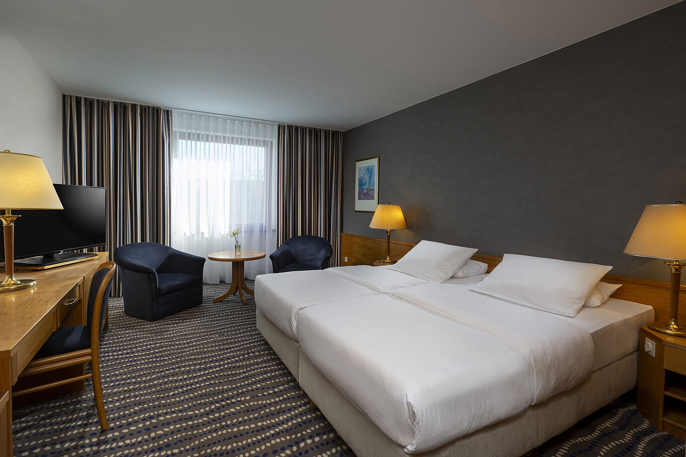 Hotel room with double bed, TV, desk, and cozy seating area, ideal for relaxation and comfort