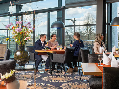 Wintergarten Restaurant Guests enjoying a meal in the restaurant at Maritim Hotel Dresden with outdoor views.