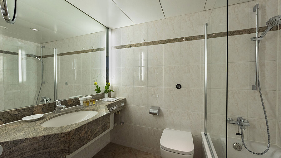 Baño luminoso con lavabo de granito, espejo y ducha – Maritim Hotel Travemünde