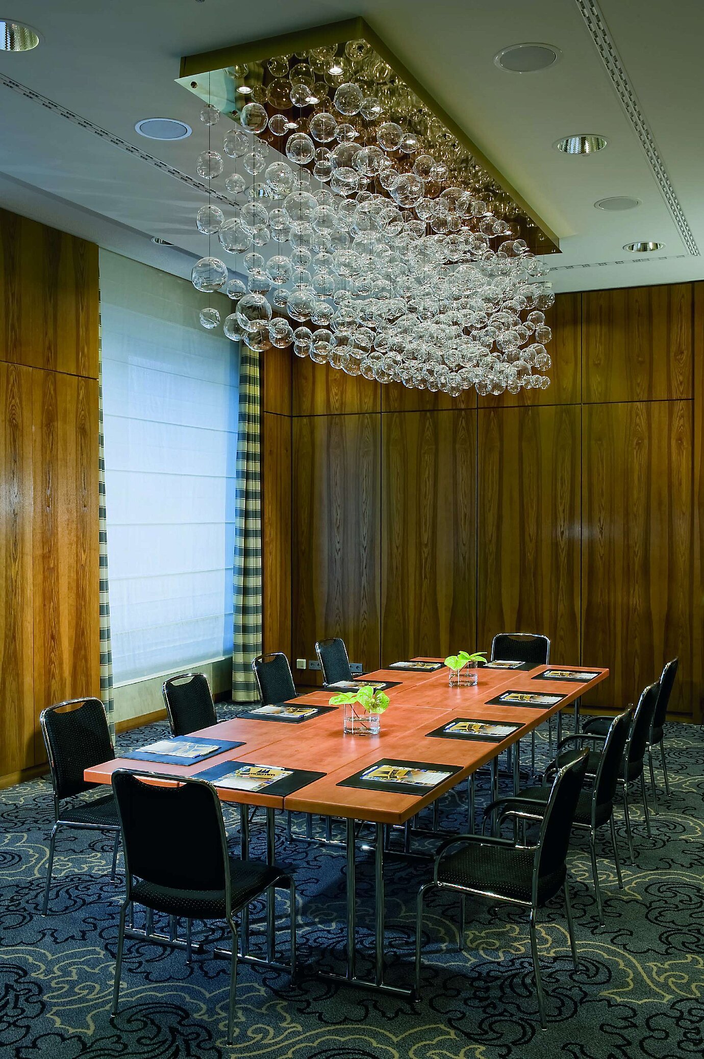 Sala de reuniones exclusiva en el Maritim Hotel Düsseldorf con mesa elegante, instalaciones modernas y lámpara única.