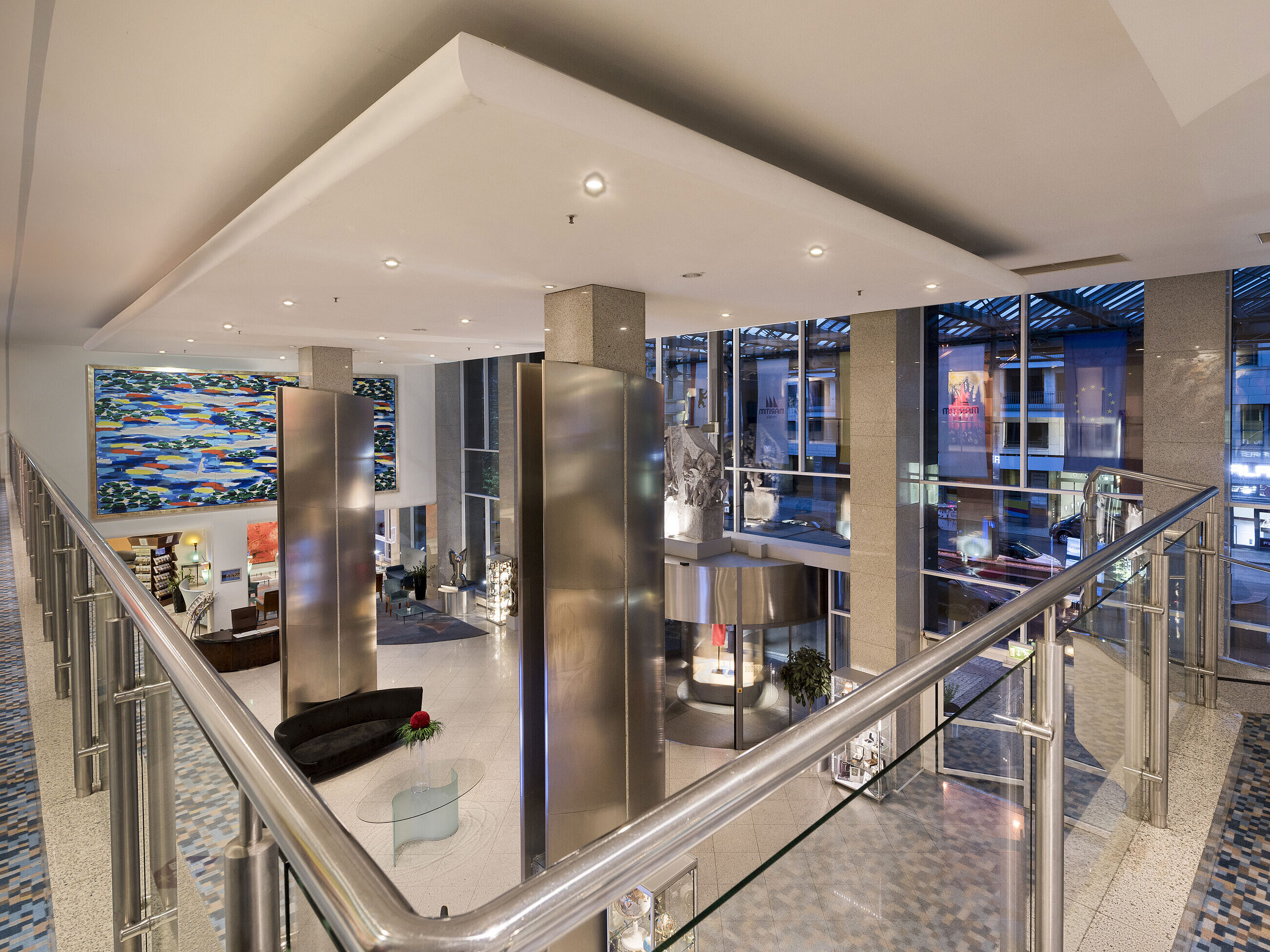 Vista dall'alto della moderna hall del Maritim proArte Hotel Berlino con grande opera d'arte e pareti di vetro.