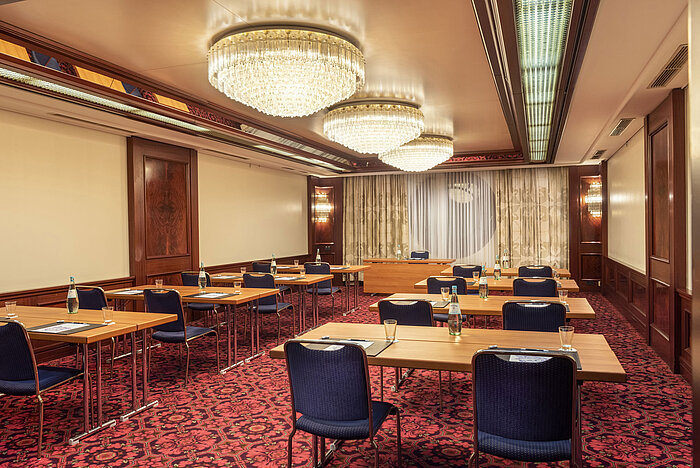Salón Bonn en Maritim Colonia, la sala está preparada para un evento con mesas, sillas y botellas de agua.