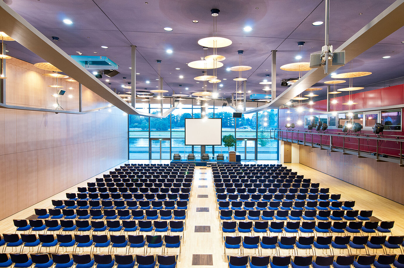 Gran sala de conferencias del Maritim Hotel Dresde con filas de sillas azules y vista al río Elba.