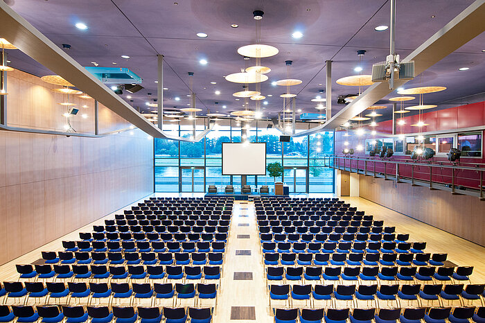Gran sala de conferencias del Maritim Hotel Dresde con filas de sillas azules y vista al río Elba.