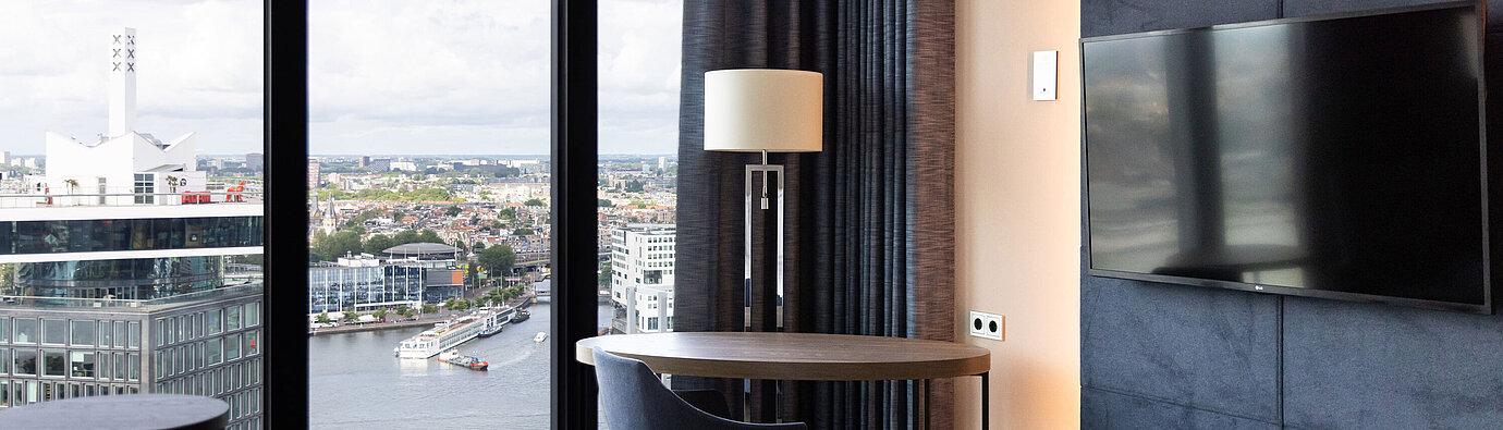 Area salotto con tavolo e vista su Amsterdam al Maritim Hotel Amsterdam