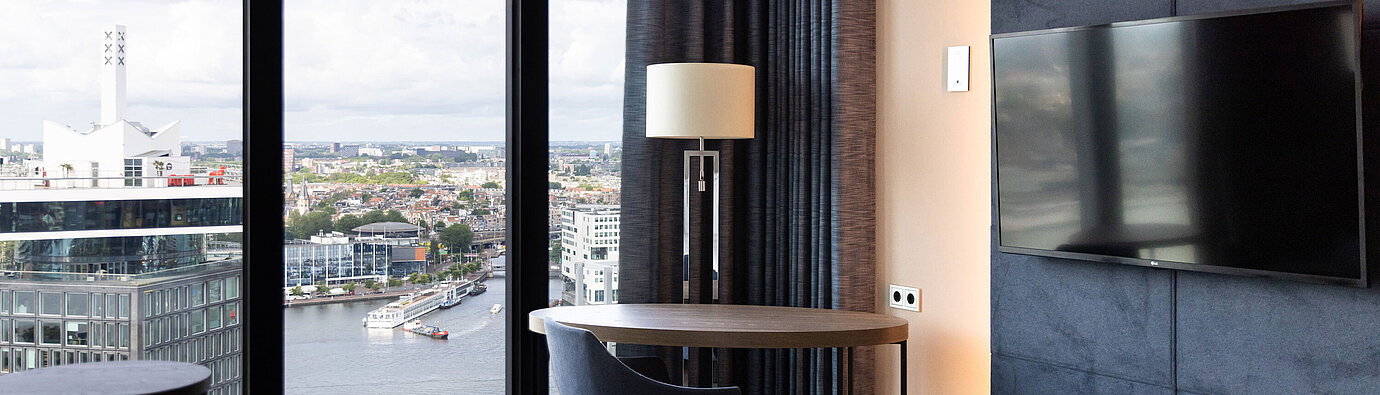 Area salotto con tavolo e vista su Amsterdam al Maritim Hotel Amsterdam