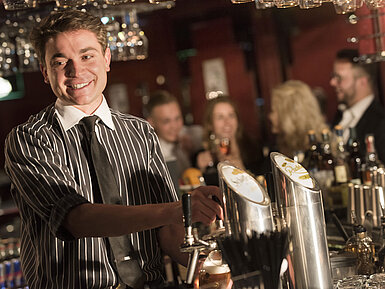 Barista cordiale serve drink nel raffinato bar del Maritim Hotel Frankfurt.
