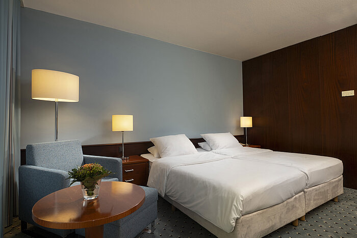  Habitación clásica en el Maritim Hotel Darmstadt con cama doble, sillón e iluminación tenue.