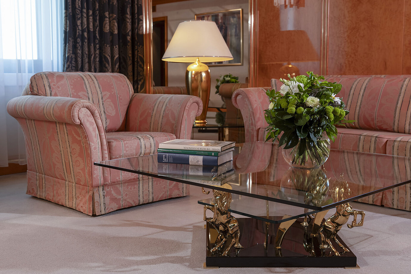 Sala de estar elegante en Maritim Hotel Hannover con zona de asientos refinada y mesa de café de vidrio.