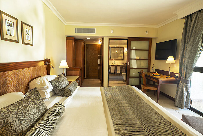 Hotel room with workspace, view into the bathroom, and stylish furniture
