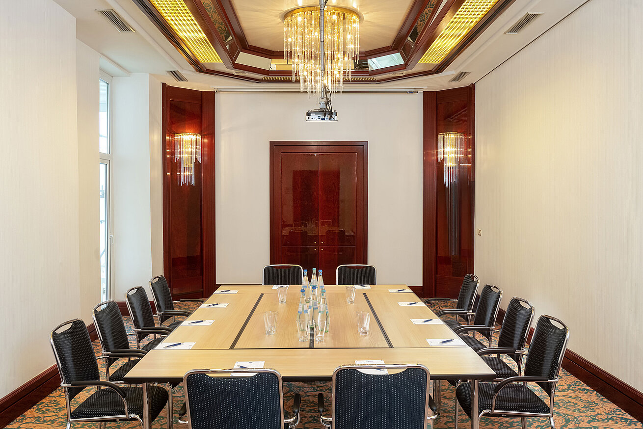 Sala Gustav Stresemann con asientos en forma de U, decoración elegante y gran lámpara en el Maritim Hotel Bad Wildungen.