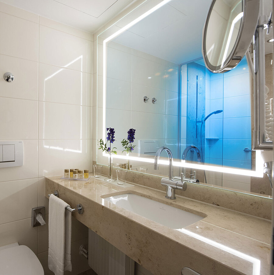 Bagno luminoso con grande specchio e prodotti al Maritim Hotel Titisee