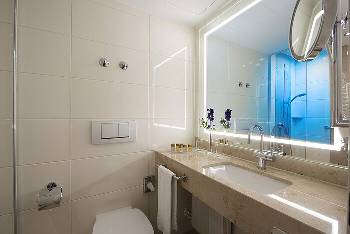 Bagno luminoso con grande specchio e prodotti al Maritim Hotel Titisee