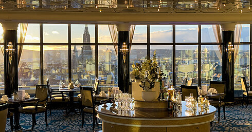 Elegante restaurante en Maritim Hotel Ulm con grandes ventanales panorámicos y vistas a la ciudad al atardecer