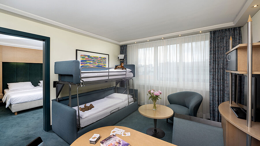 Suite familiar con litera, sofá, mesa y vista al dormitorio en Maritim proArte Hotel Berlin