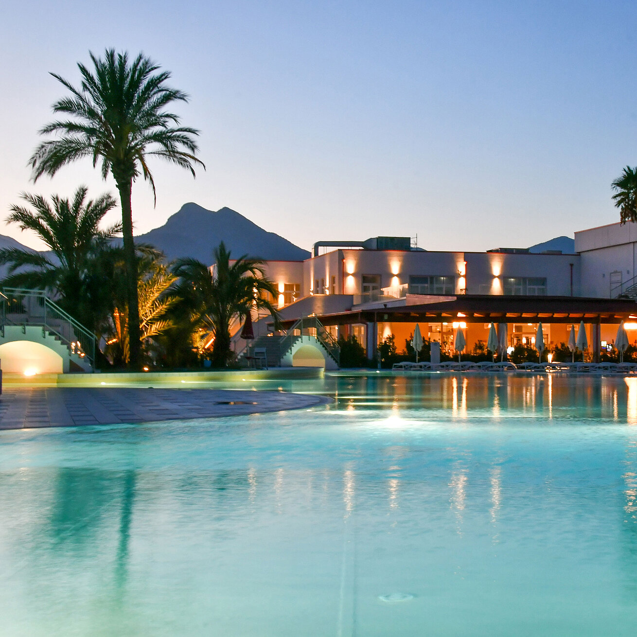 Pool Evening lights at the pool of Maritim Resort Calabria with palm trees and mountain backdrop