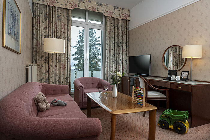 Coin salon familial avec jouets, canapé, TV et balcon au Maritim Hotel Bad Wildungen