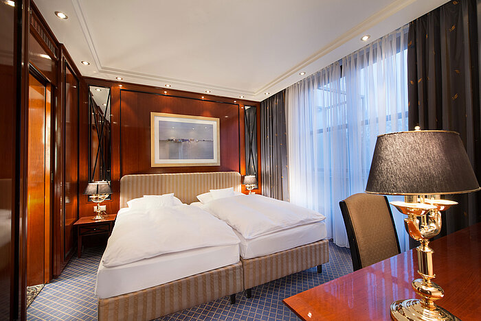 Suite elegante al Maritim Hotel Fulda con letto doppio lussuoso, dettagli in legno e illuminazione accogliente.