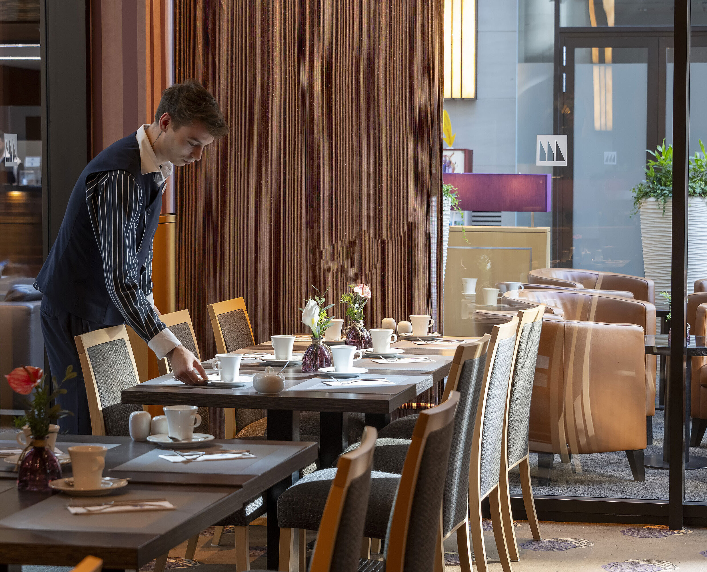 Membre du personnel préparant une table au restaurant Classico de l'hôtel Maritim Düsseldorf,entouré d'une décoration élégante