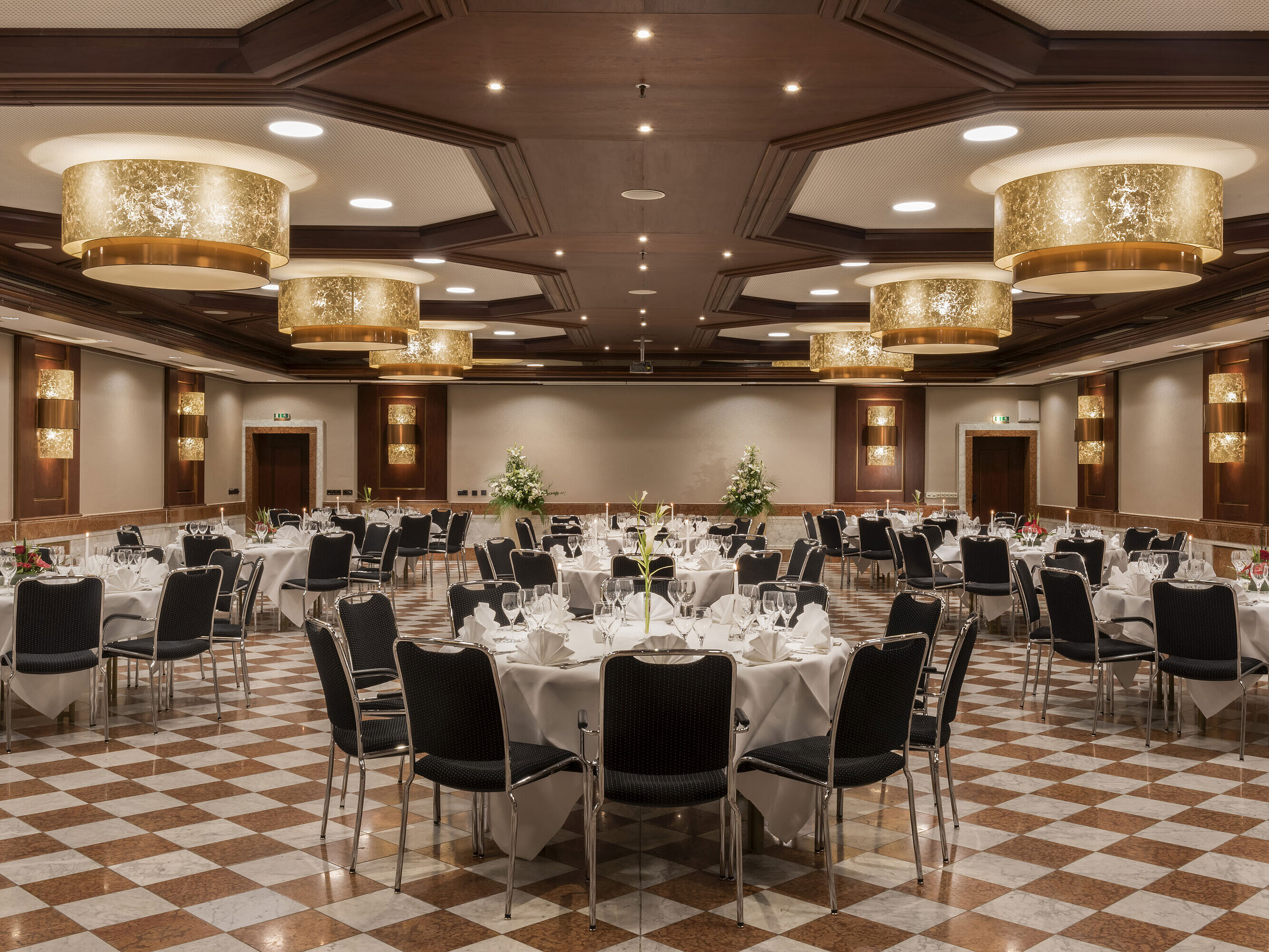 Élégante salle de banquet au Maritim Hotel Königswinter avec tables rondes, décor raffiné et lustres.