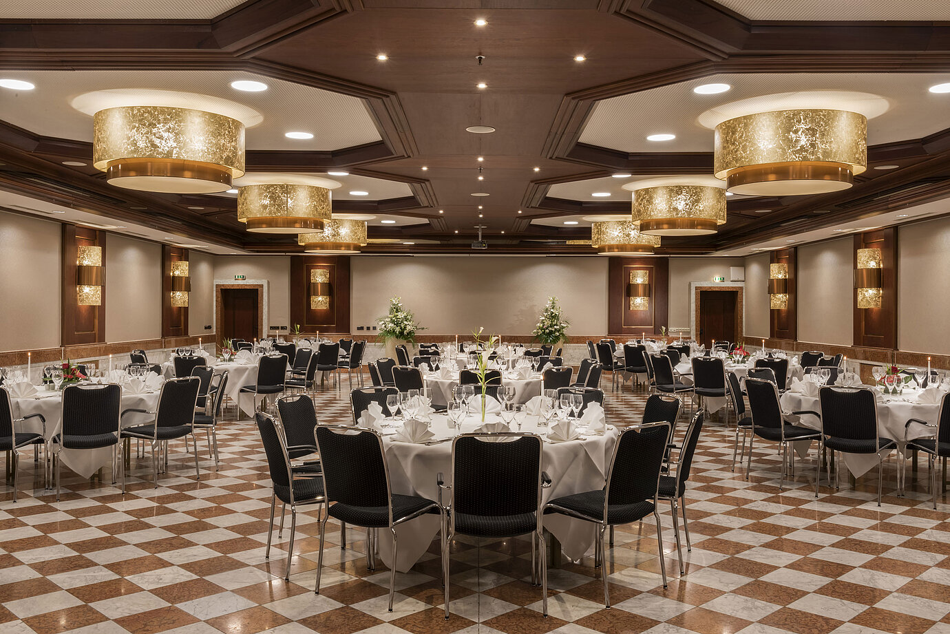 Élégante salle de banquet au Maritim Hotel Königswinter avec tables rondes, décor raffiné et lustres.