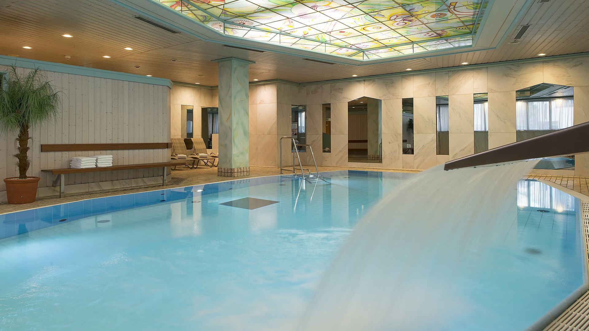 Piscine chauffée avec cascade et plafond en verre coloré à l’hôtel Maritim Stuttgart