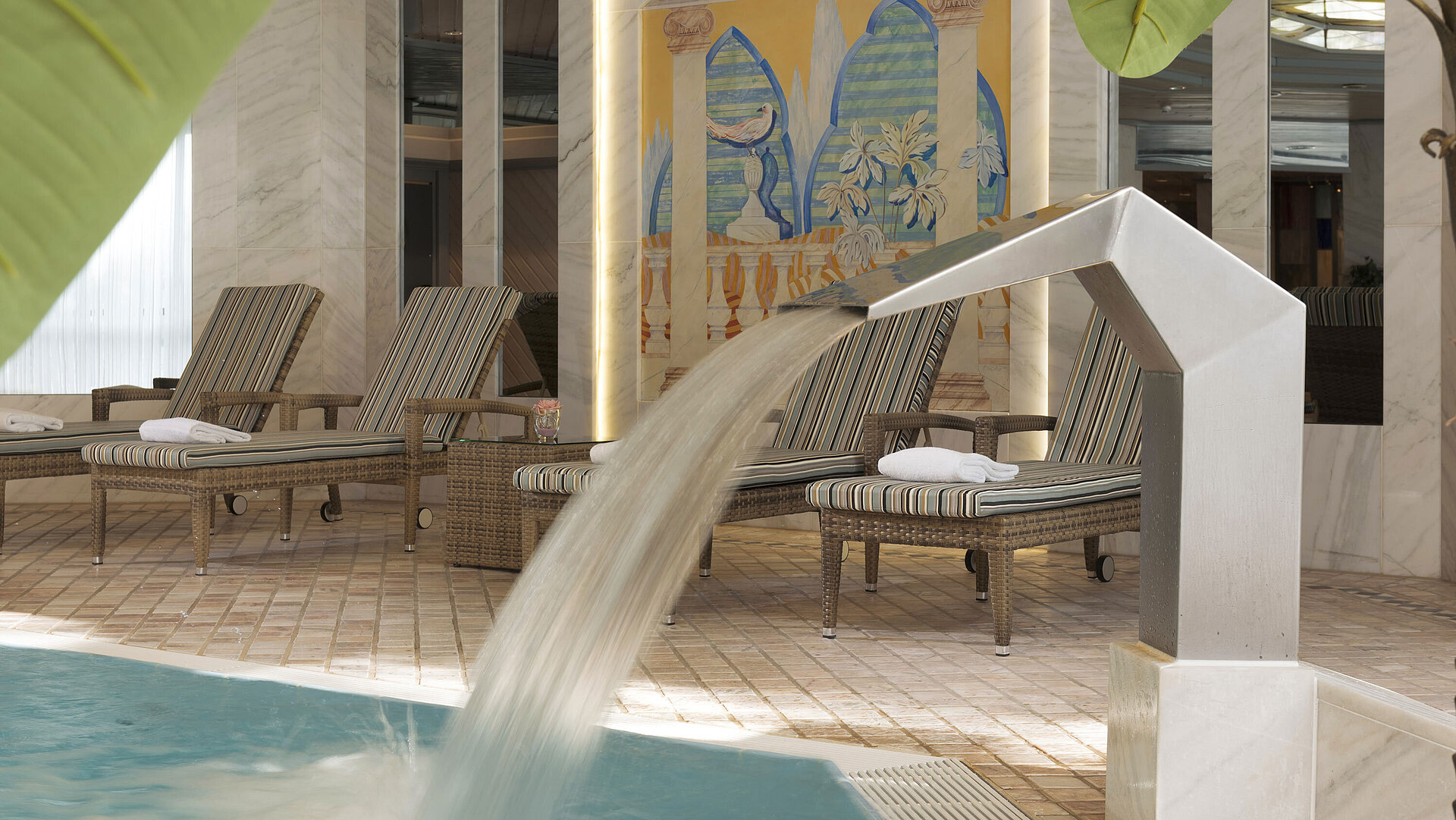 Piscine intérieure moderne avec cascade et transats à l’hôtel Maritim Ulm pour une pause détente.