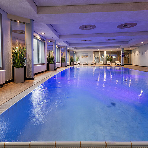 Piscina cubierta iluminada del Maritim Hotel Frankfurt con ambiente relajante y ventanales panorámicos.