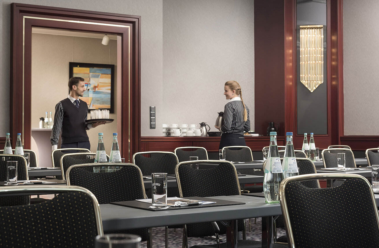 Elegante sala de conferencias en Maritim Hotel Hannover con servicio atento, botellas de agua y cómodos asientos.