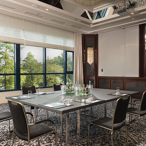 Sala de conferencias luminosa en Maritim Hotel Hannover con ventanales grandes, vista verde y diseño elegante.