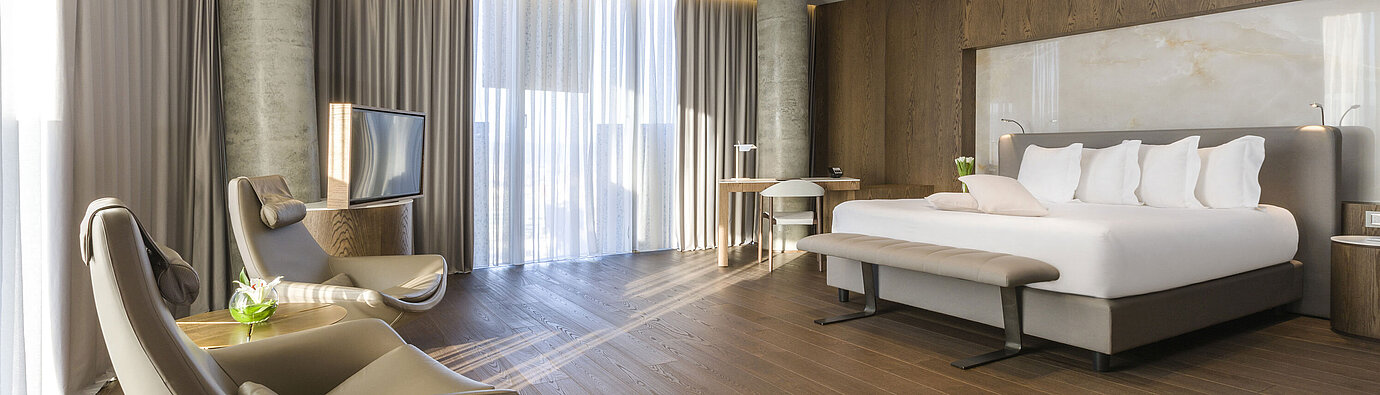 Habitación amplia con ventanas panorámicas, sillones y diseño moderno en Maritim Hotel Plaza Tirana