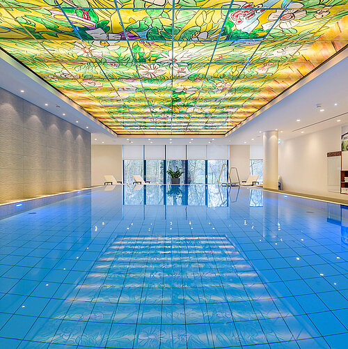 Elegante area piscina al Maritim Bremen con soffitto in vetro colorato e illuminazione moderna,perfetta per relax e benessere