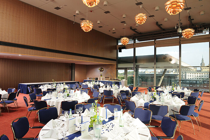 Elegante sala de eventos del Maritim Hotel Dresde con mesas decoradas y vista a la ciudad.