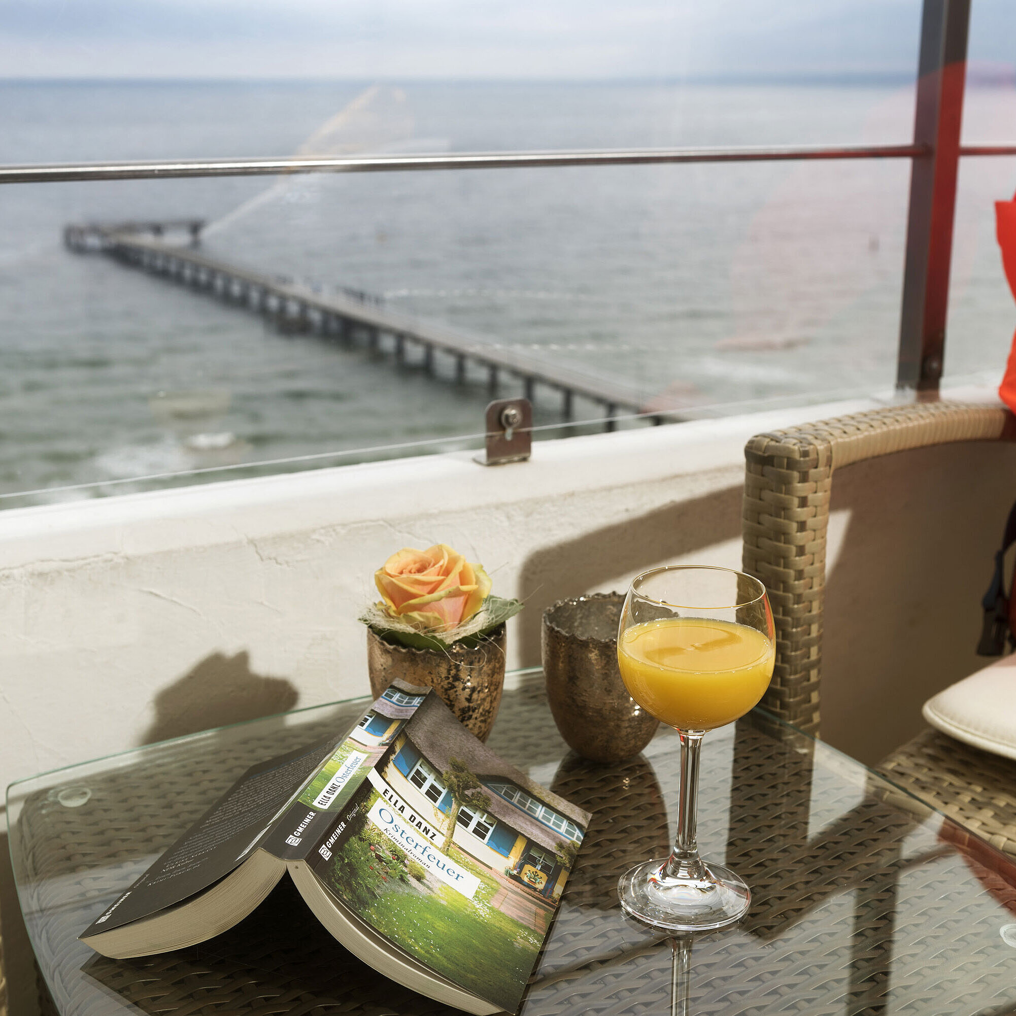 Balcón con vista al mar Balcón con vista al mar, vaso de jugo de naranja, libro y chaleco salvavidas en Maritim Seehotel Timmendorfer Strand.