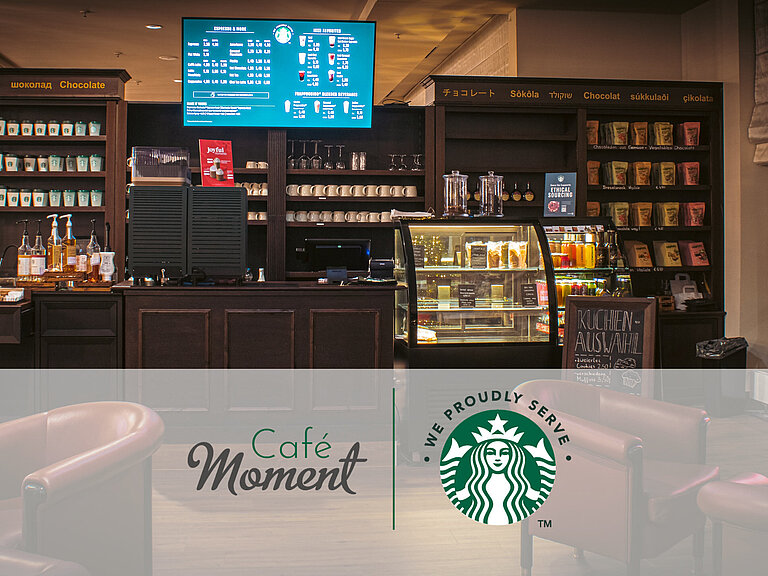 Café (proudly serves Sturbucks) Café del Maritim Hotel Bonn con café Starbucks, mostrador de snacks, vitrina de pasteles y asientos acogedores