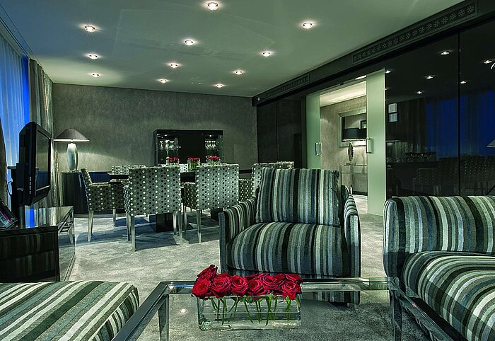 Sala de estar de la Master Suite en el Maritim Hotel Düsseldorf con muebles modernos, mesa de comedor estilizada y luz cálida