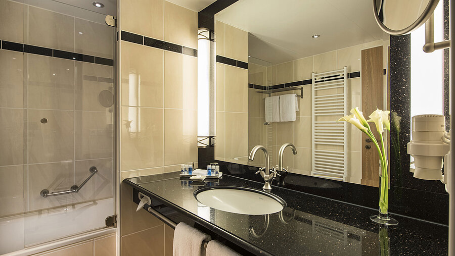Salle de bain moderne avec lavabo, miroir, baignoire et détails élégants à l'hôtel Maritim Dresden.