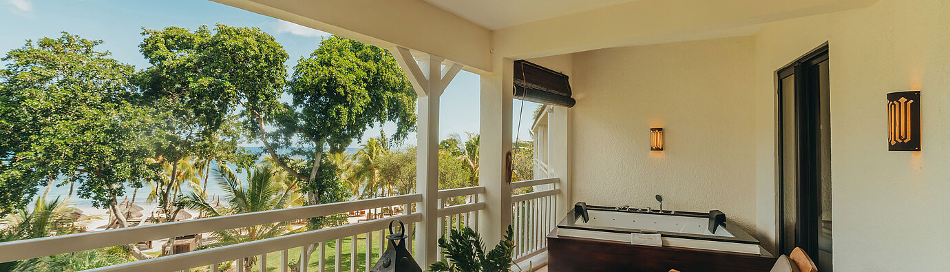 Penthouse Suite Terrace of the Penthouse Suite with seating, sun loungers and views of tropical greenery and the sea.