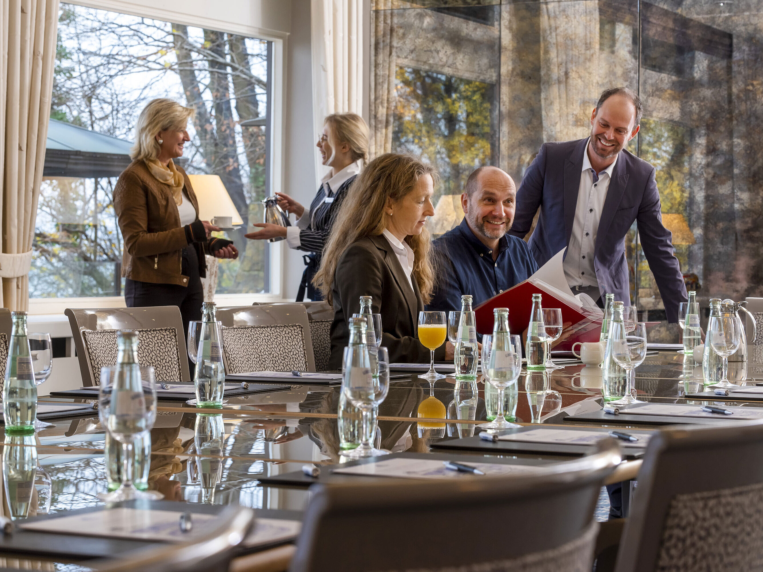 Salón Oslo en el Maritim Hotel Kiel, los participantes en una reunión, ambiente relajado con bebidas y un servicio amable.