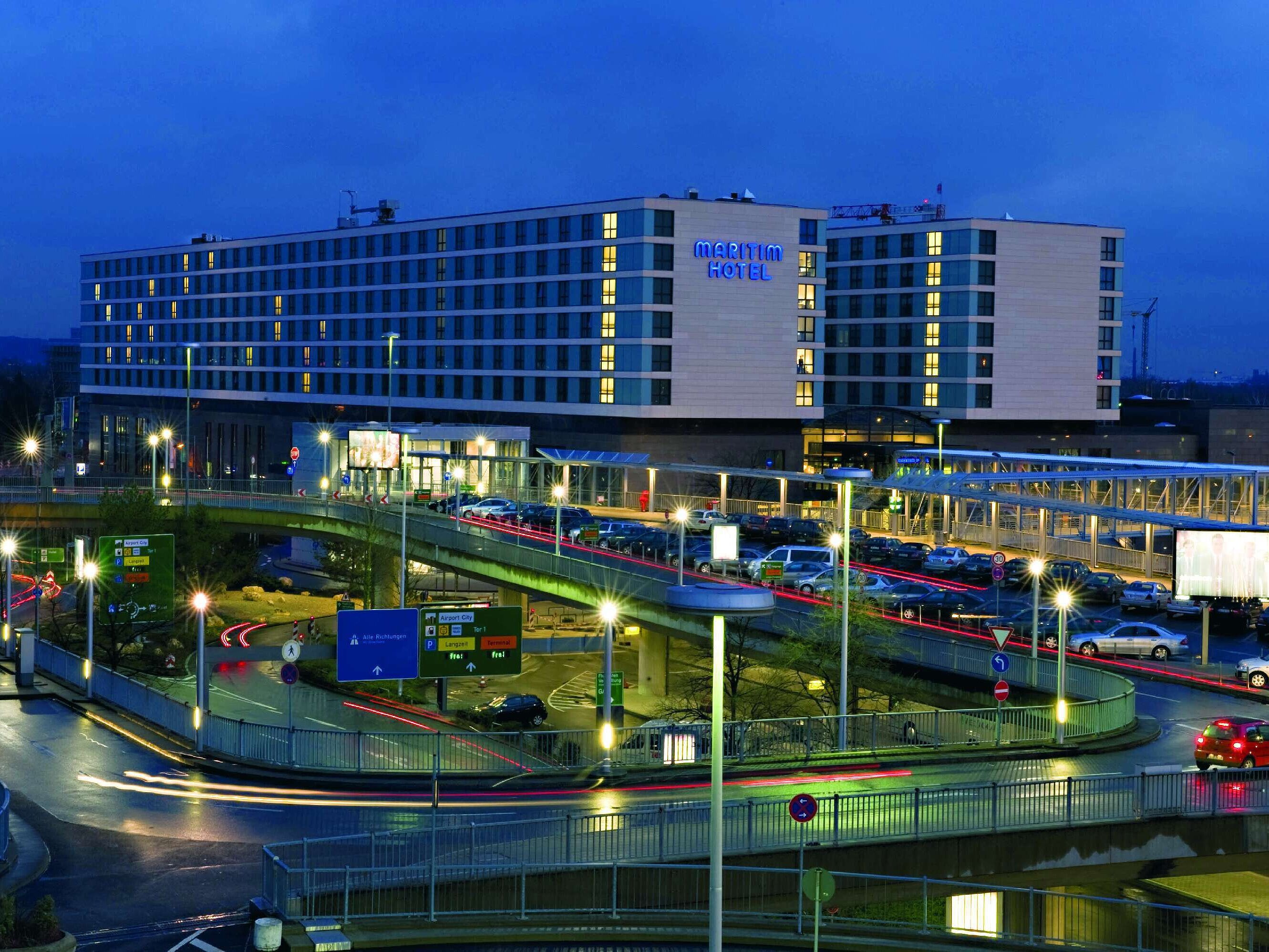 Night view of Maritim Hotel Düsseldorf with illuminated facade, direct airport location, and modern architecture.